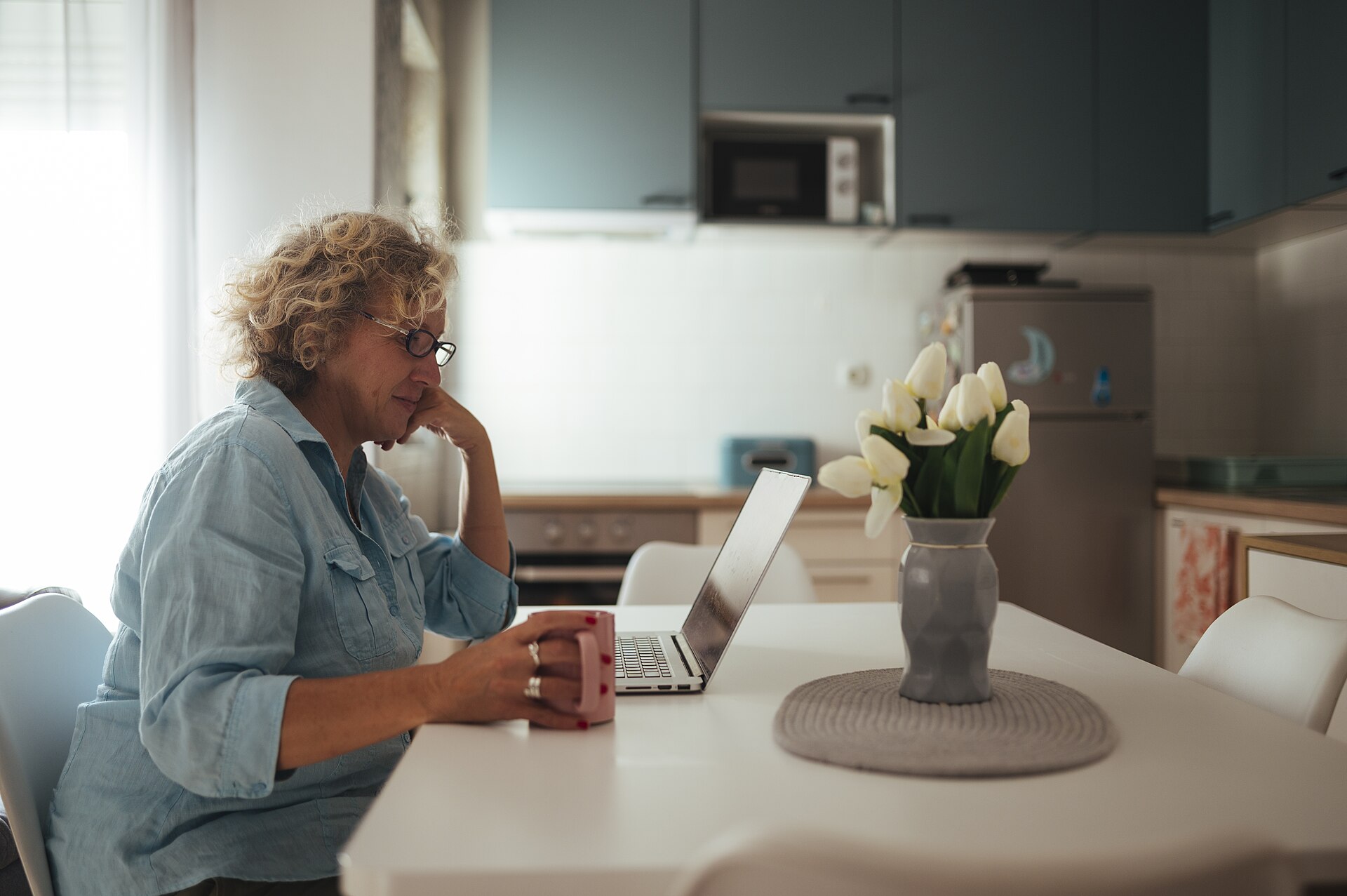 Een rustig moment aan de keukentafel met een laptop en een kop koffie
